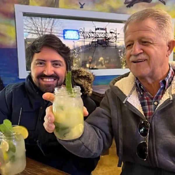 Two men smiling and holding mojitos at The Hush Cuban Kitchen.